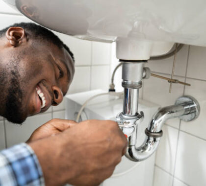 Plumber Fixing Pipe In Bathroom. Plumbing Maintenance In Bathroom